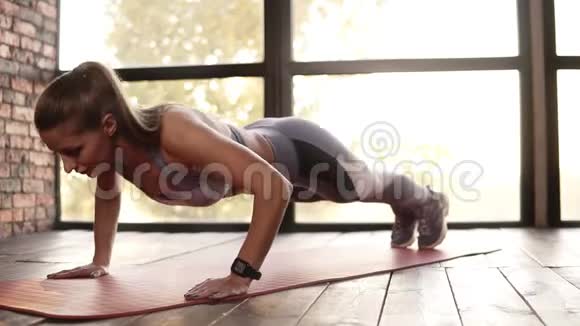 运动美女做俯卧撑作为锻炼的一部分穿灰色紧身裤和胸罩的金发女人做俯卧撑运动视频的预览图