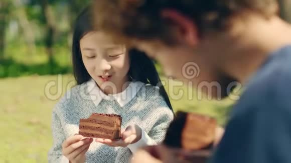 亚洲小女孩和白种人男孩在户外吃蛋糕视频的预览图