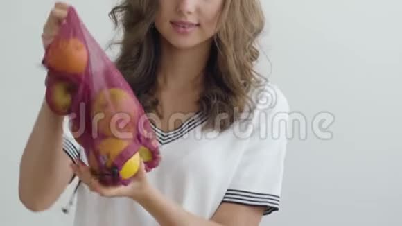 年轻苗条的女人在现代厨房里从桌子上的一个袋子里倒苹果健康食品的概念营养学专业视频的预览图