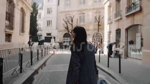 欢快美丽的旅行女性带着相机摆姿势沿着秋天的巴黎街道微笑慢动作视频的预览图
