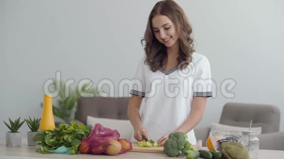年轻的技巧可爱的女人用锋利的刀在厨房的桌子上切蔬菜健康食品的概念视频的预览图