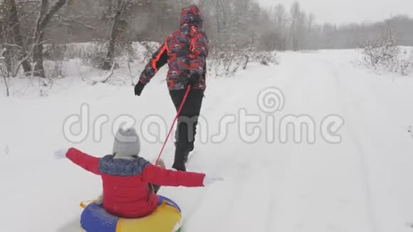 快乐的爸爸是幸运的在一个孩子雪白的道路上雪橇圣诞节假期和旅行为成年人提供一个有趣的游戏视频的预览图