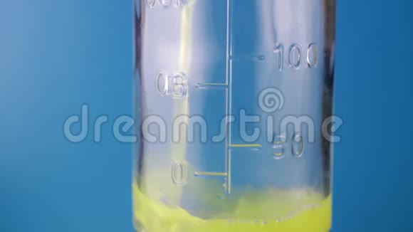 一种彩色化学液体在蓝色背景下倒入玻璃测量瓶中的特写镜头经验概念视频的预览图
