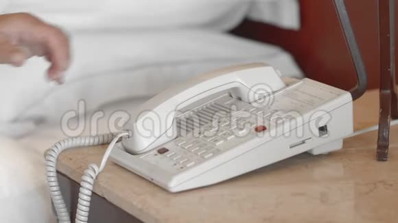 未被认出的穿着白色浴袍的成年高级妇女在酒店房间拿起电话接电话慢动作视频的预览图