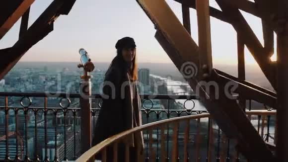 年轻迷人的欧洲女人看着相机沿着巴黎埃菲尔铁塔金属酒吧在日落天空缓慢的运动视频的预览图