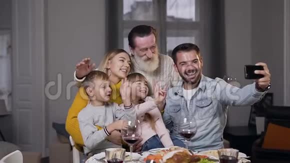 坐在餐桌前自拍的迷人笑家庭的正面景色视频的预览图
