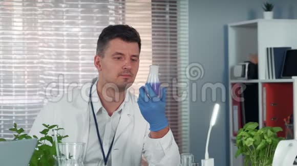 实验过程中观察锥形瓶中液体反应的英俊的科学家视频的预览图