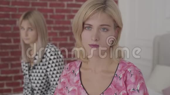 一个受伤的白种人女人的肖像穿着粉红色睡衣背对着朋友坐着金发美女吵架了视频的预览图