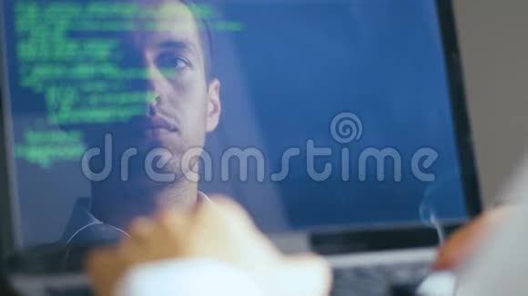 在笔记本电脑上工作的人黑客程序员的双曝光镜头监视器中的反射开发人员编写绿色代码视频的预览图