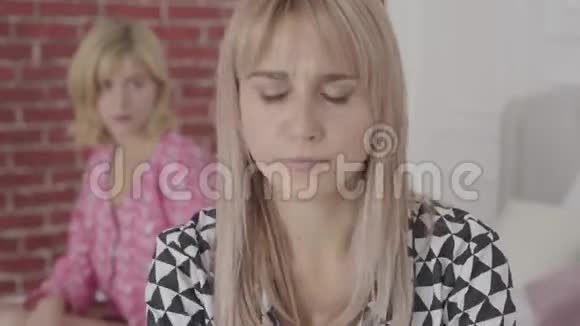 一个愤怒的年轻白种人女人的肖像灰色的眼睛坐着背对着朋友金发美女视频的预览图