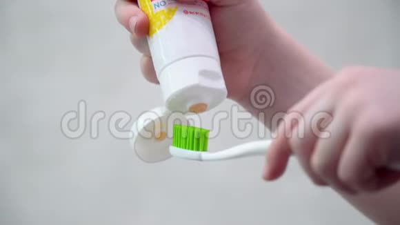 孩子在卫生间刷牙小男孩把牙膏涂在刷子上视频的预览图