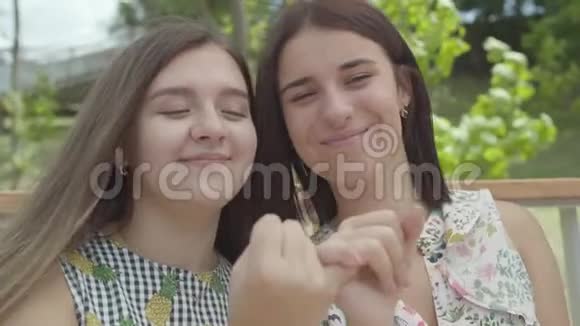 肖像两个可爱的女孩互相拿着对方小手指和微笑看着镜头简洁的手势视频的预览图