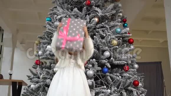 小女孩把礼盒扔了起来圣诞节的气氛和孩子身后的树视频的预览图