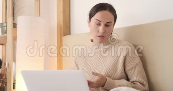 女人在卧室的笔记本电脑上聊天视频的预览图