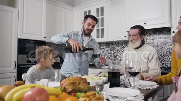 感恩节庆祝活动中留着胡子的好心人把酒倒入酒杯中送给长辈们视频的预览图