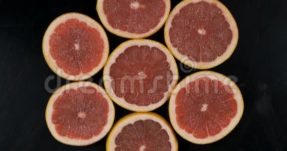 黑色背景下新鲜葡萄柚切片的收集旋转柑橘果实上景视频的预览图
