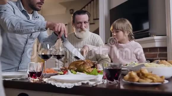 一个漂亮的女孩向她的父亲展示她想在感恩节庆祝时吃哪一部分烤火鸡视频的预览图