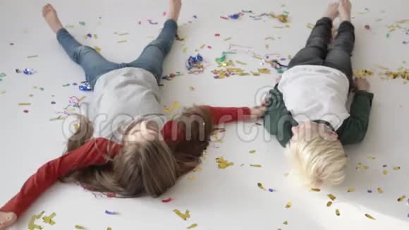 快乐的孩子在白色地板上玩纸屑视频的预览图