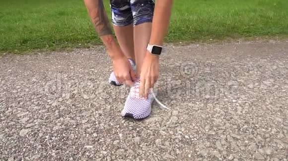 女性慢跑者在跑鞋上系鞋带的慢动作镜头视频的预览图