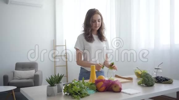 美丽的白种人苗条的女人用手在厨房的桌子上撕绿色健康食品的概念果果果视频的预览图