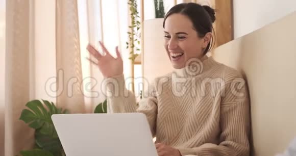 女人在床上用笔记本电脑打视频电话视频的预览图