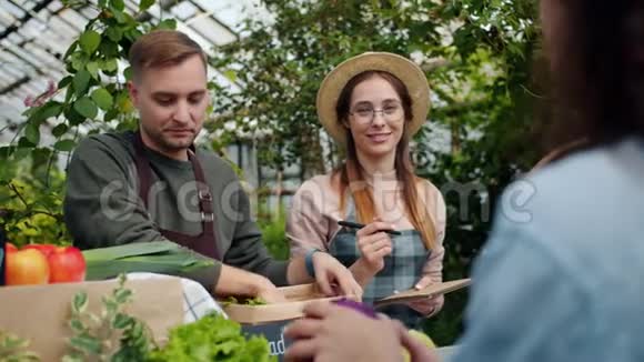 友好的销售人员在农场市场包装有机食品与顾客交谈视频的预览图