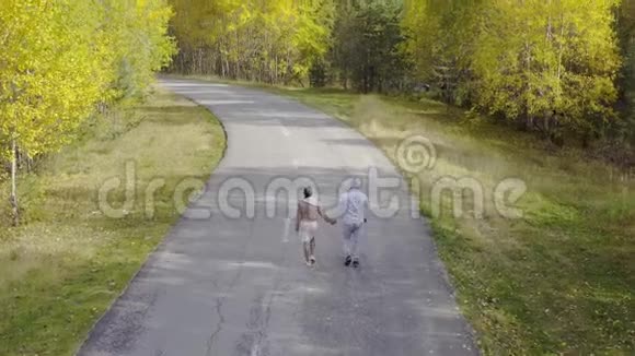 雄雌一对走在秋林中的柏油路上上景视频的预览图