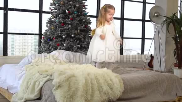圣诞节那天一个快乐的小女孩在家里跳着床视频的预览图