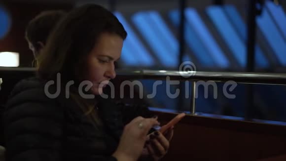 女人坐在渡轮公共空间和冲浪社交网络视频的预览图
