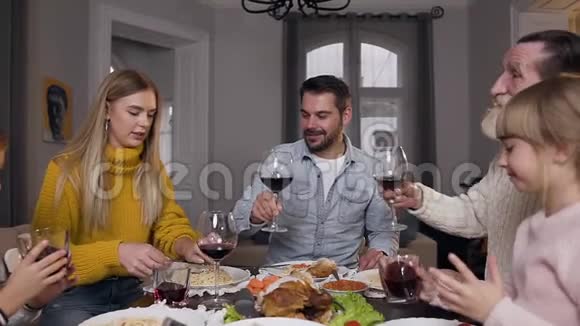 坐在喜宴旁碰杯的不同世代可爱家庭的迷人画像视频的预览图