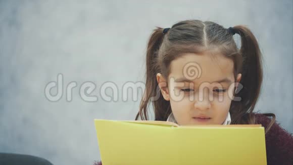 一个勤奋的小女生坐在桌边看书灰色背景视频的预览图