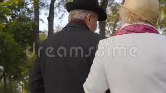 一个穿着黑色帽子和外套的黑色帽子和外套的白种人成熟男人走在他妻子旁边已婚夫妇视频的预览图