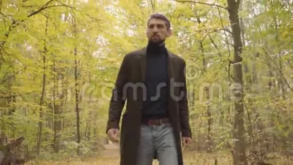 一个英俊自信的白人男子穿着休闲服在森林里散步一个灰发棕色的家伙视频的预览图