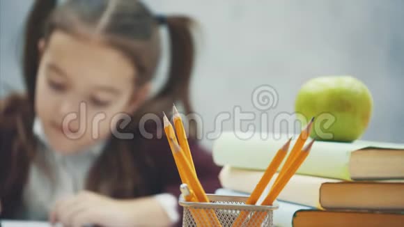 在灰色背景下关闭女学生在这段时间里他坐在桌子旁不能拿铅笔视频的预览图
