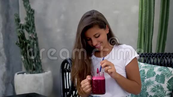 一个年轻的黑发女孩坐在一家咖啡馆里手里拿着一个新鲜的甜菜根新鲜蔬菜视频的预览图