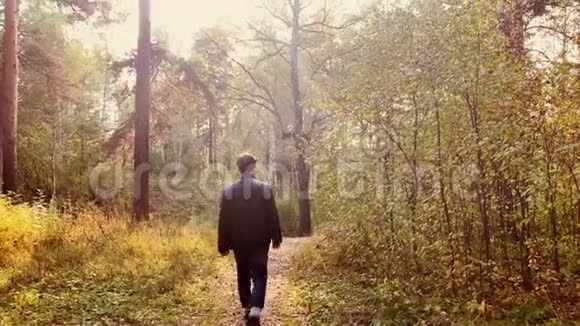 穿黑色夹克的人在晴天在公园散步秋林路景观视频的预览图