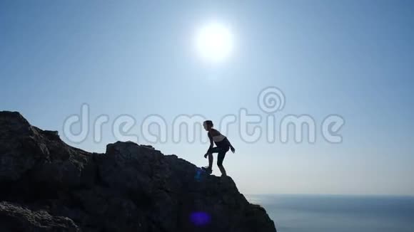 自信的年轻女子在日出时缓慢地走向山顶一位女士徒步旅行的剪影视频的预览图