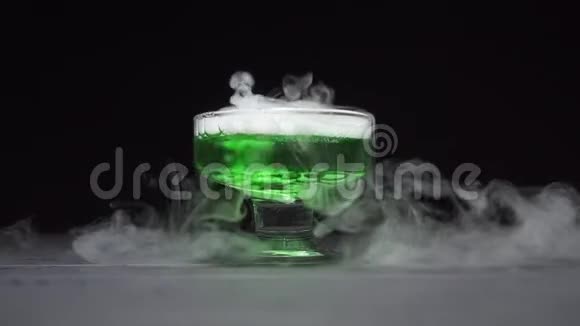 绿色液体沸腾在黑色背景下的玻璃碗中散发烟雾视频的预览图