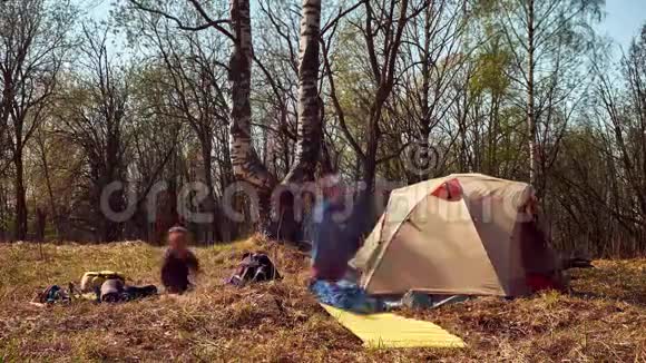 一家人在初春与模糊的人徒步旅行时包装帐篷的长时间暴露时间视频的预览图