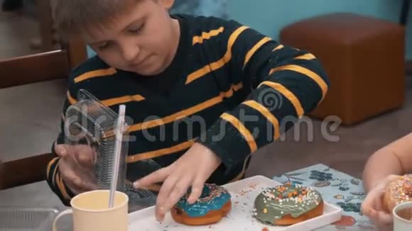 可爱的小男孩把甜甜圈放进塑料盒子视频的预览图