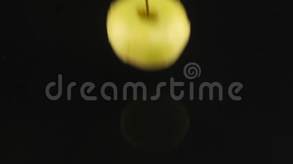成熟多汁的苹果切片落在一个覆盖着水的黑色表面上慢动作视频的预览图