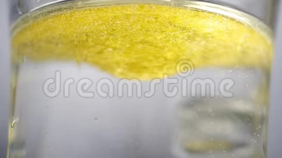 黄色液体与水混合在玻璃中用小勺子特写油不与水混合视频的预览图
