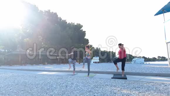 三个女人早上在空海滩做瑜伽有镜头耀斑效应视频的预览图