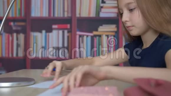女生在书架背景上用钢笔写字学生女孩在舒适的办公室写作业视频的预览图