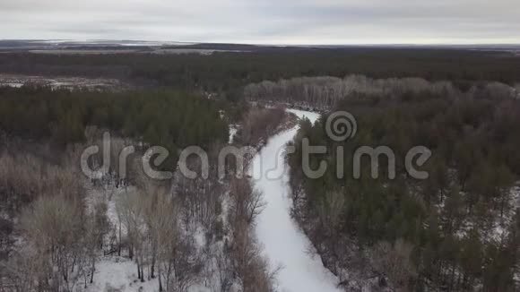 冬季森林里冰冻的河流从无人机俯瞰视频的预览图