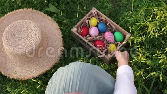 女孩把帽子放在草地上拿起一盒复活节彩蛋视频的预览图