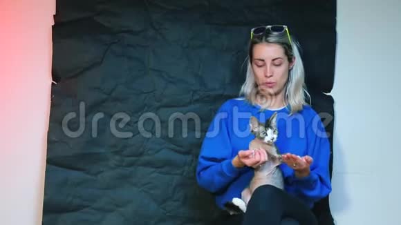 一个穿蓝色衣服的女孩怀里抱着一只德文雷克斯猫视频的预览图