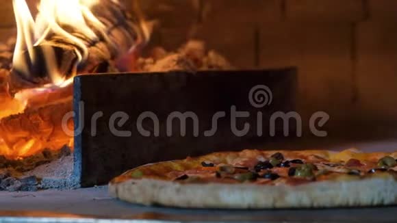 意大利披萨和西红柿是在烤箱里煮的餐馆厨师在餐馆的木头烤箱里拿披萨视频的预览图