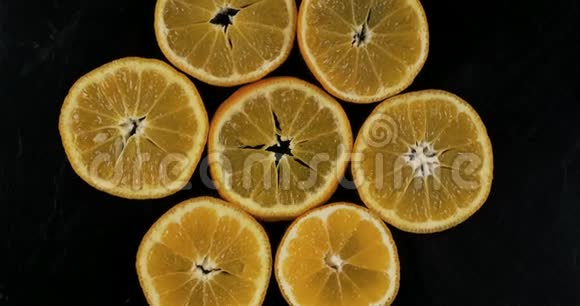 在黑色背景上收集新鲜的普通话切片旋转柑橘果实上景视频的预览图