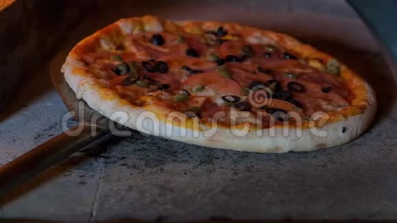 意大利披萨和西红柿是在烤箱里煮的餐馆厨师在餐馆的木头烤箱里拿披萨视频的预览图